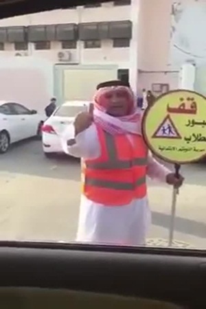 شاهد معلم يرفع لافتة أمام إحدى المدارس
