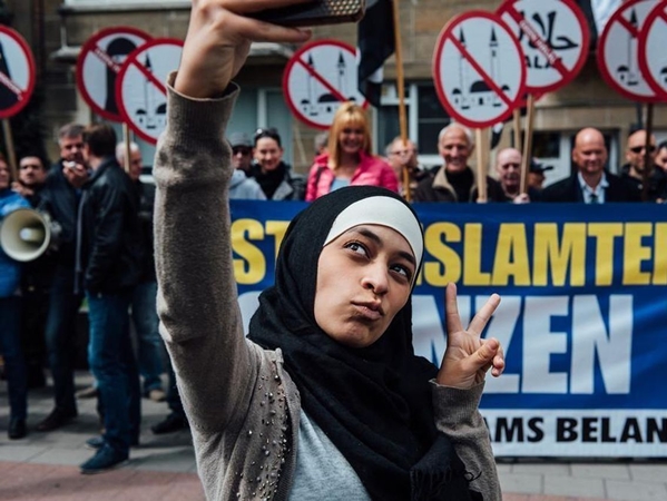 فتاة مسلمة تصور نفسها مع متظاهرين ضد الإسلام