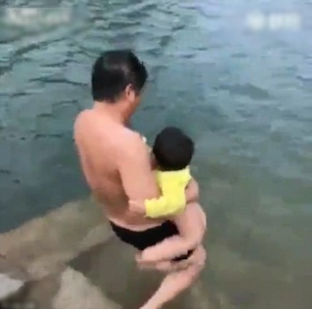أب يلقي ابنه عاريًا في البحيرة كي يعلمه السباحة .. ويثير الغضب بهذا الفيديو