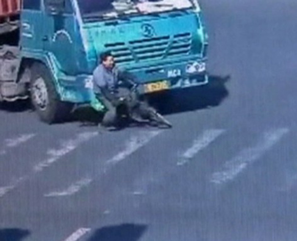 بالفيديو: سائق دراجة ينجو من الموت بعد مرور شاحنة فوقه